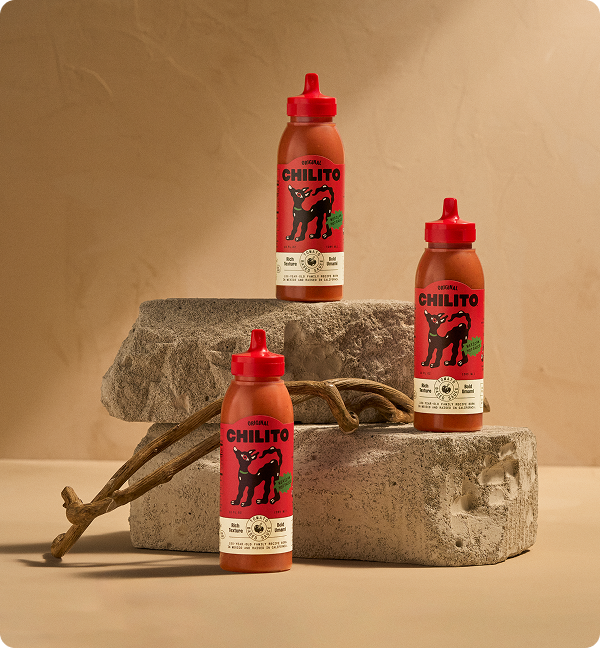 Three bottles of Chilito hot sauce on a stone surface with a beige background