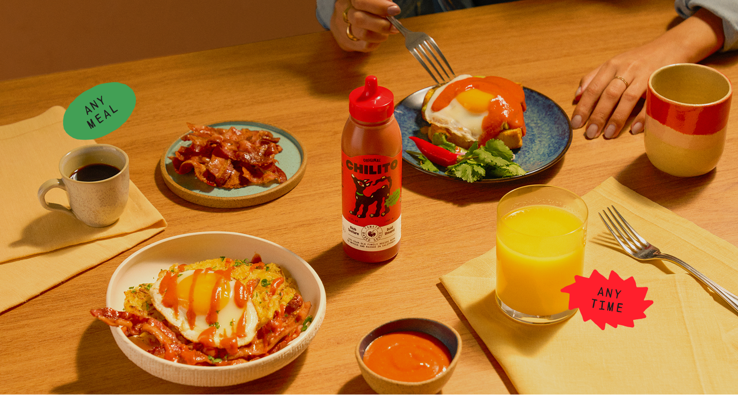 Dining table with food, drinks, and a bottle of hot sauce.
