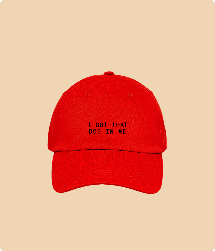Red cap with text 'I GOT THAT DOG IN ME' on a beige background