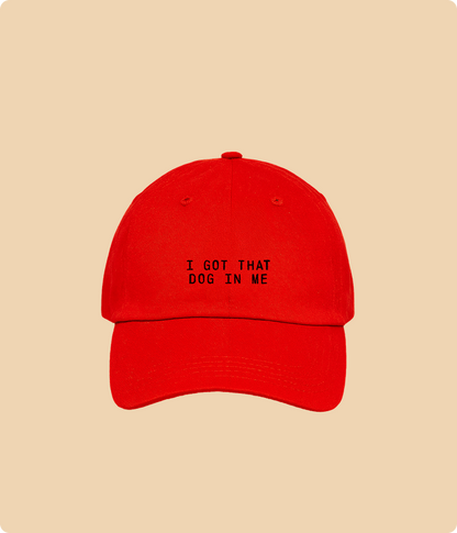 Red cap with text 'I GOT THAT DOG IN ME' on a beige background