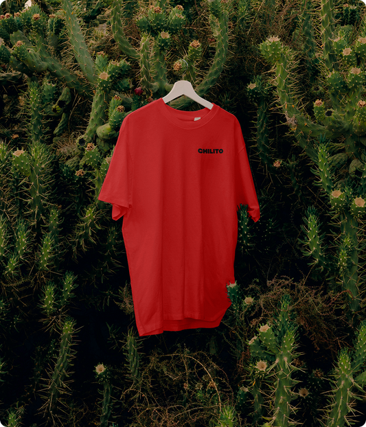 Red t-shirt with text on a hanger against a cactus background