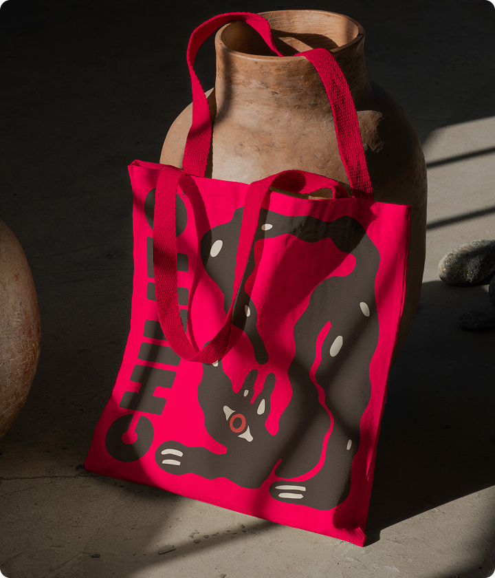 Red tote bag with black and white design on a dark surface